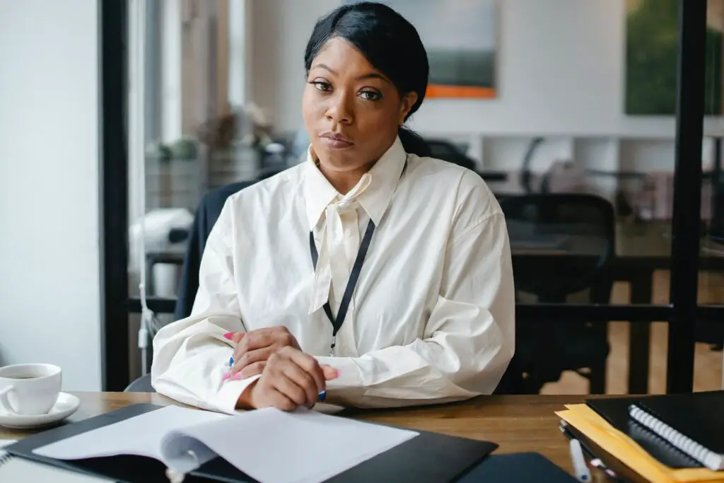 Black women sitting at a desk in an office, working a salaried job.